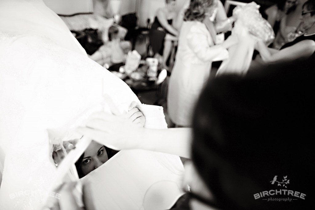 bride's face peeking out as she puts on her wedding dress
