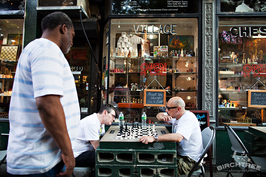two men playing chess in manhattan suburb, while another watches closely