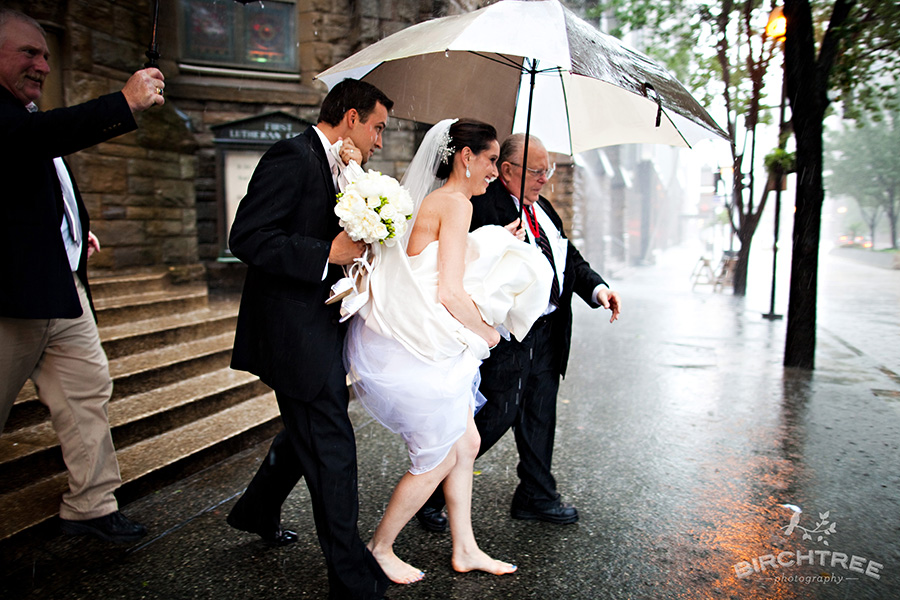 bride and groom running to car in rain on wedding day